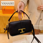 Black handbag with gold logo held by a person, Vanaski brand visible