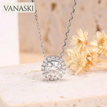 Silver necklace with a diamond pendant on a soft background with flowers.