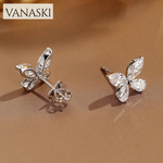 Butterfly-shaped earrings withVanaski branding on a brown background