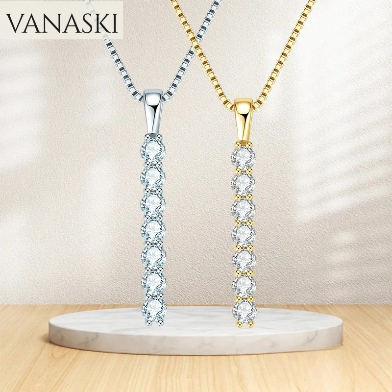 Two diamond pendants, one gold and one silver, on a beige background with 'VANASKI' branding.