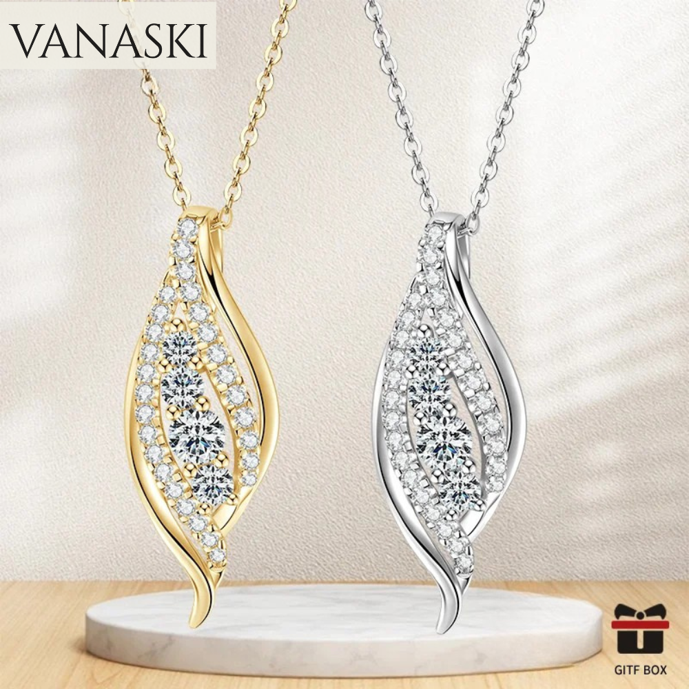 Two leaf-shaped necklaces, one gold and one silver, on a beige background with 'VANASKI' branding.