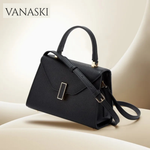 Black handbag with gold accents on a beige surface, featuring the Vanaski brand.