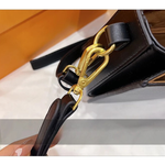 Close-up of a black handbag with a gold clasp on a white background