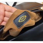 Brown leather glove with Todés label held by a hand