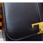 Black leather handbag with a gold clasp on a blurred background