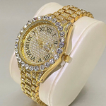 Gold watch with diamond-studded face and band on a white cushion