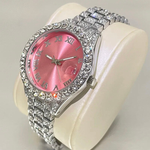 Pink watch with a silver and crystal-encrusted band on a white cushion