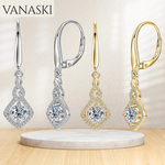Pair of silver and gold earrings with gemstones on a beige background, featuring the Vanaski brand.