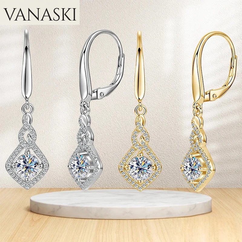 Pair of silver and gold earrings with gemstones on a beige background, featuring the Vanaski brand.