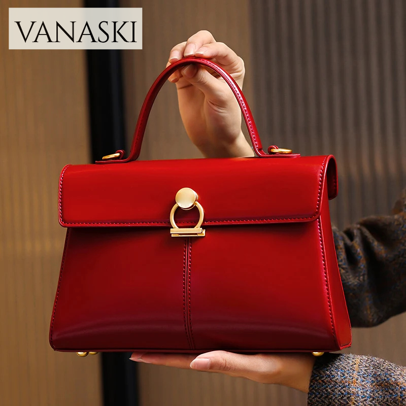 Red handbag with gold accents held by a person, featuring the Vanaski brand.