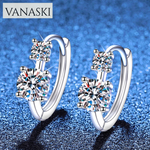 Silver hoop earrings with clear gemstones on a blue glittery background, featuring the Vanaski brand.